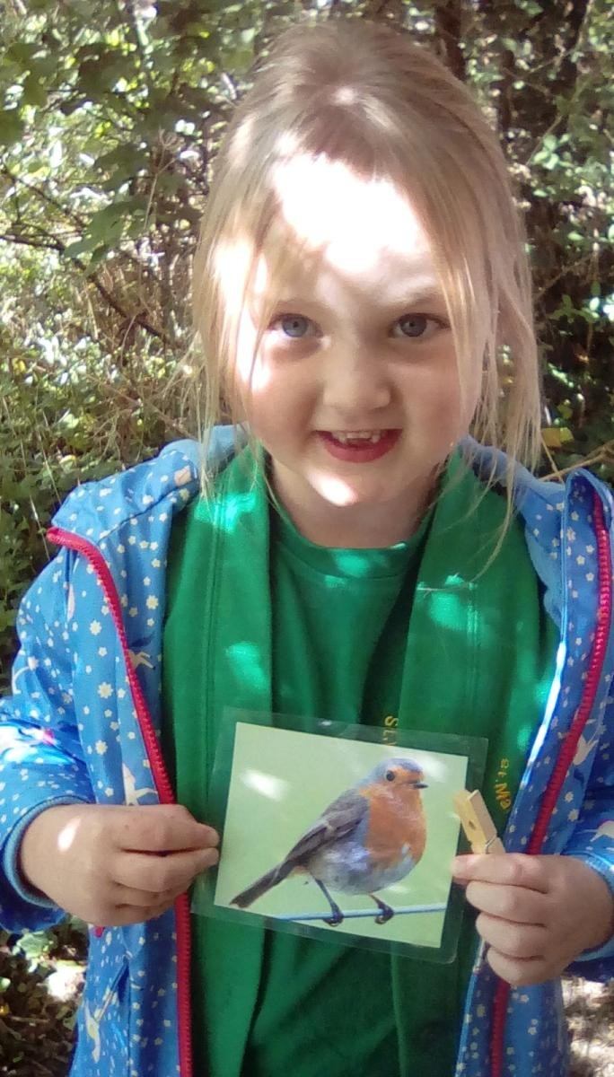 Smiling child holding a photo of a robin