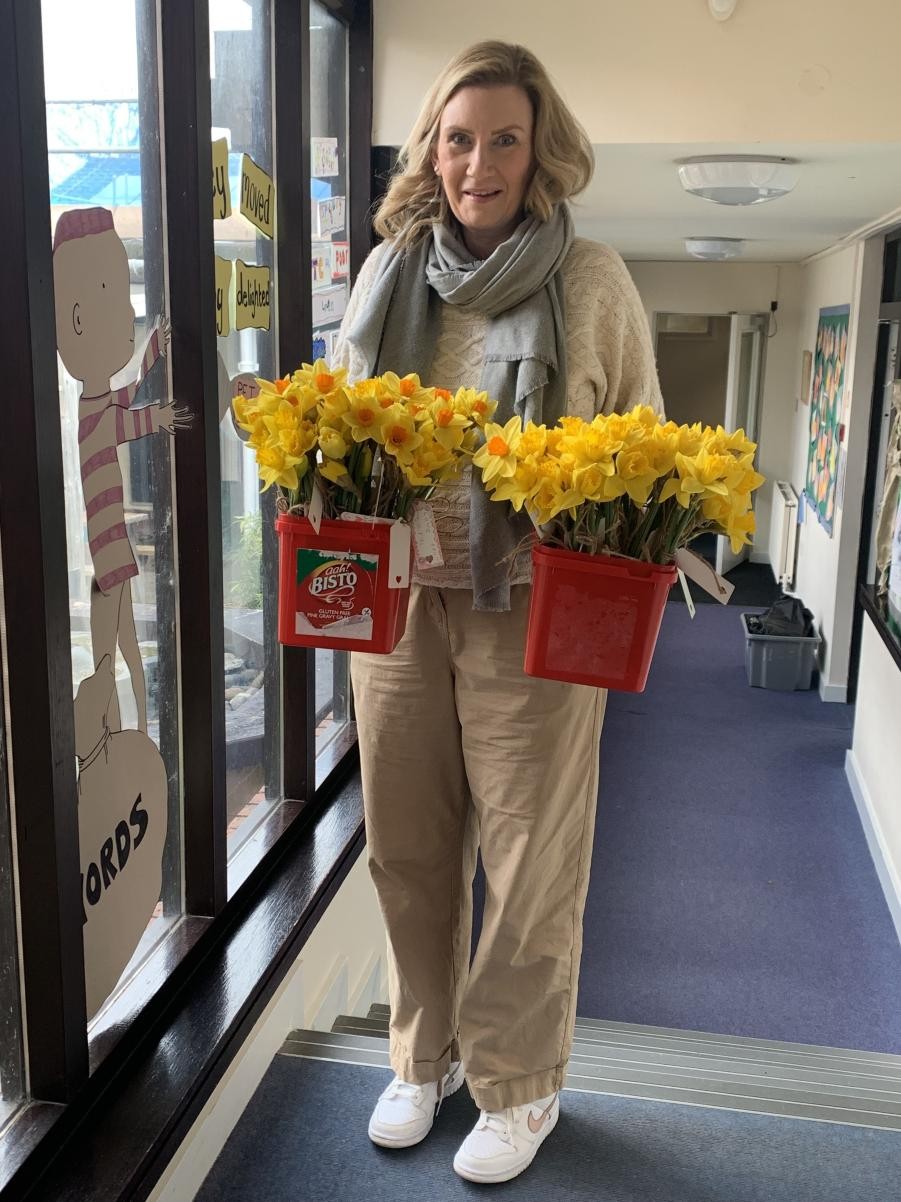 School Association Flowers A happy lady holding two buckets of daffodils